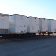 Five trailers side by side in a parking lot.