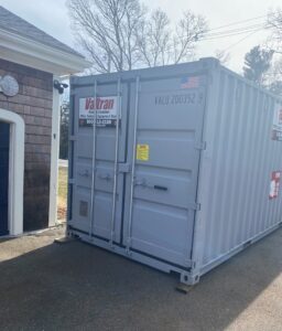 A Valtran storage container conveniently positioned next to a homeowner's garage door, illustrating its use for personal storage.