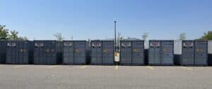 Seven grey Valtran storage containers lined up in a parking lot for event storage.